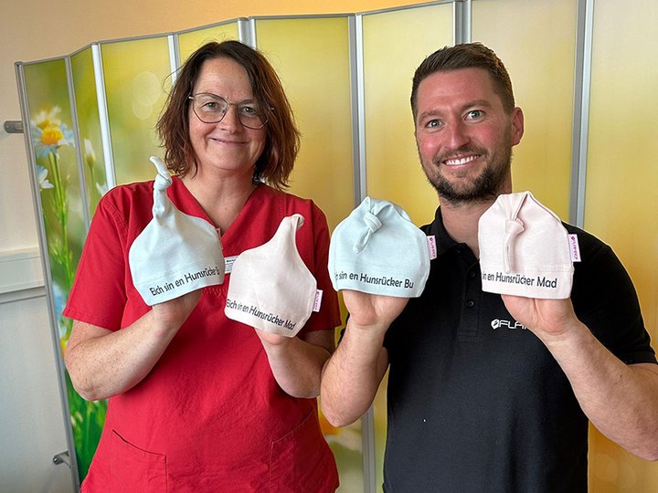 Ein Mitarbeiter von Flamro übergibt die Babymützen an die Leiterin der Neugeborenenstation