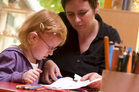 Mädchen und Erzieherin im Kindergarten beim Ausschneiden