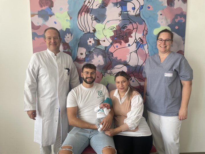 4 Personen und 1 Baby lächeln in die Kamera