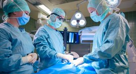 Eine Frau und zwei Männer operieren eine verstopfte Halsschlagader