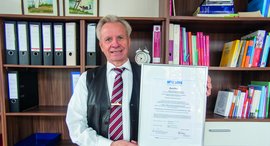 Mann hält eine Urkunde in die Kamera