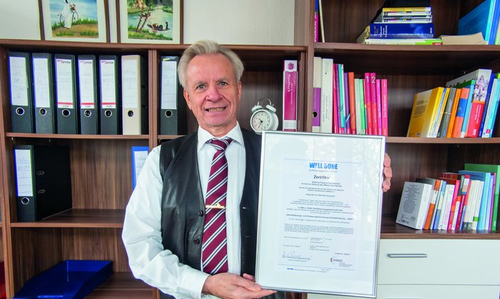 Mann hält eine Urkunde in die Kamera