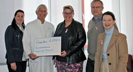 Arzt bekommt von drei Frauen und einem Mann einen symbolischen Scheck überreicht