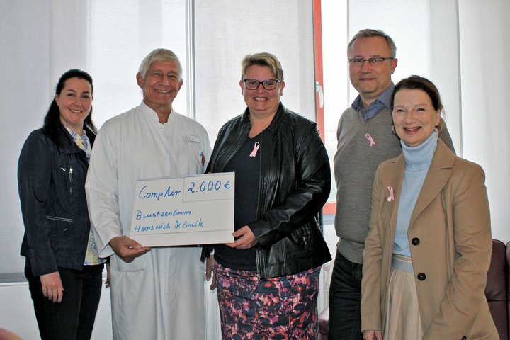 Arzt bekommt von drei Frauen und einem Mann einen symbolischen Scheck überreicht