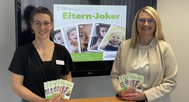 Annika Frank und Kristina Theodoropoulos zeigen die kostenlose Elternbroschüre Elternjoker