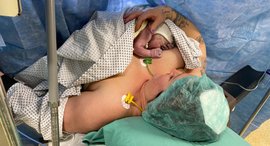 Neugeborenes liegt auf Brust der Mutter