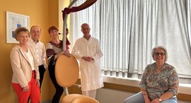 In der Mitte des Bildes steht ein Gebärstuhl. Darum stehen und sitzen mehrere Personen