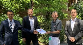 Person überreicht Urkunde an Mitarbeiter des Krankenhaues