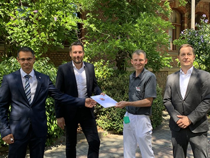 Person überreicht Urkunde an Mitarbeiter des Krankenhaues