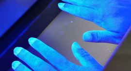 Hände werden in eine Schwarzlichtlampe gehalten