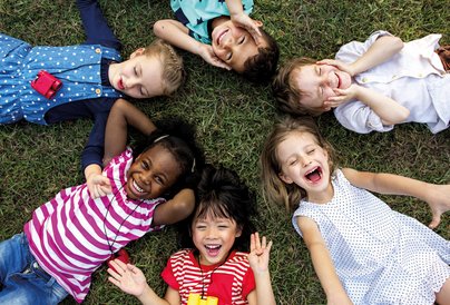 Kinder liegen im Kreis auf Wiese
