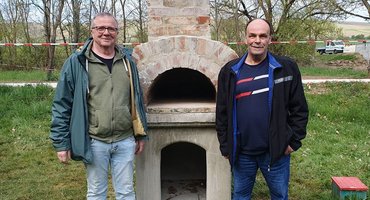 Zwei Männer stehen vor einem gemauerten Pizzaofen