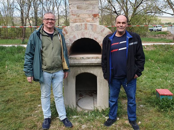Zwei Männer stehen vor einem gemauerten Pizzaofen