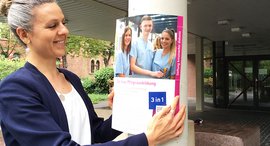 Frau hängt Plakat auf