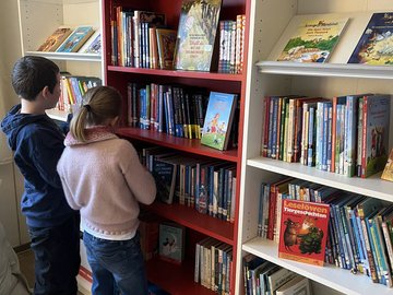 Zwei Kinder stehen vor Buchregalen