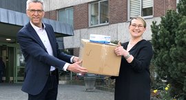 Erik Gregori überreicht die Masken an Kristina Theodoropoulos