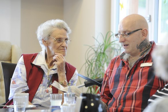 Pflegekraft liest einer Seniorin aus einem Buch vor