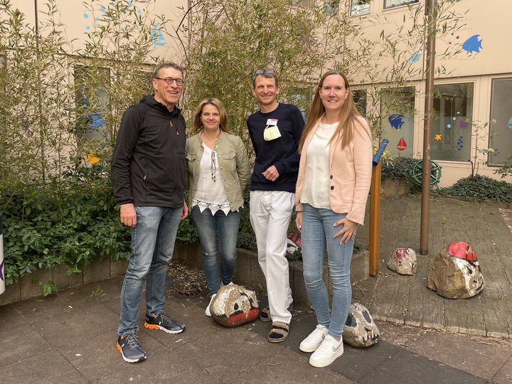 Personen stehen an einem Baum und lächeln in die Kamera