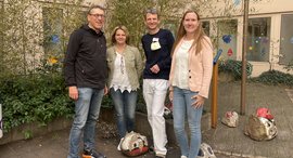 Personen stehen an einem Baum und lächeln in die Kamera