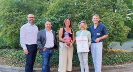 Diakonie Kliniken erhält eine Schüttel-mich-nicht-Puppe als Spende überreicht