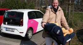 Frau mit Baby in Liegeschale - im Hintergrund Auto der Diakonie Sozialstation der Seniorenhilfe der Stiftung kreuznacher diakonie