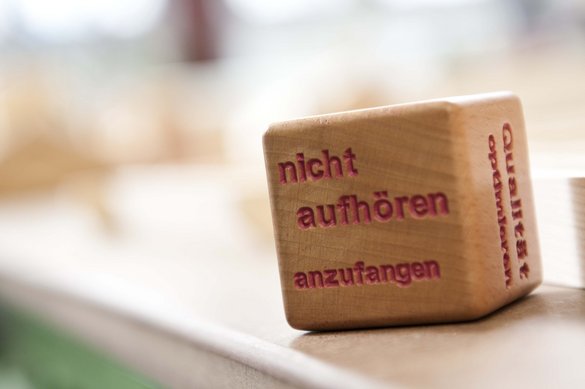 Würfel mit Leitbildsatz "Nicht aufhören anzufangen"