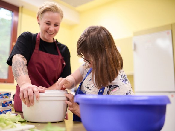 Junge Frau unterstützt Mädchen beim Kochen und Backen