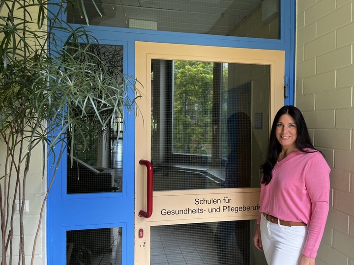 Frau steht vor Schuleingang