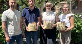 Ausbilder Marc Heimann gratuliert einem Mann und zwei Frauen zum Abschluss ihrer Ausbildung Büromanagement