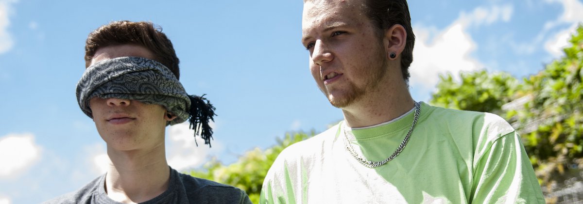 Zwei junge Männer, einer mit Augenbinde