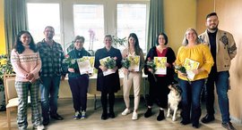 Personen lächeln mit Urkunde in Kamera