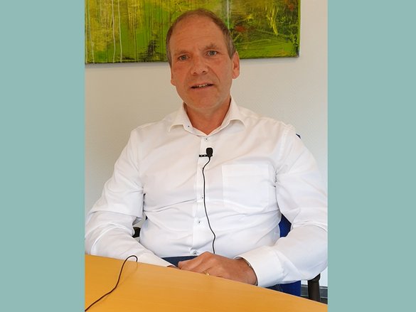 Screenshot eines Videos - Interviewsituation, Mann spricht in Mikro